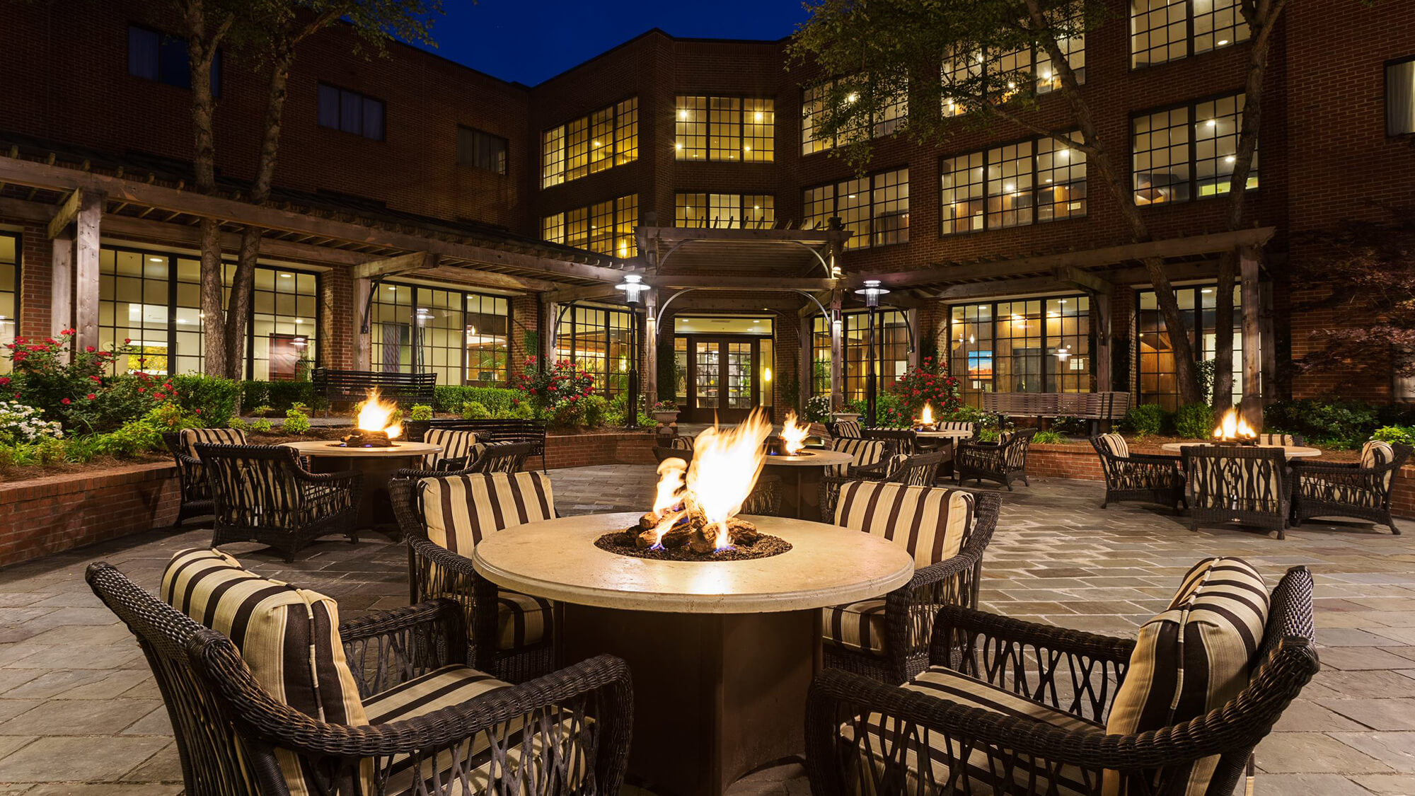 Night view of outdoor patio with firepit tables and lounge chairs in Charlotte, NC